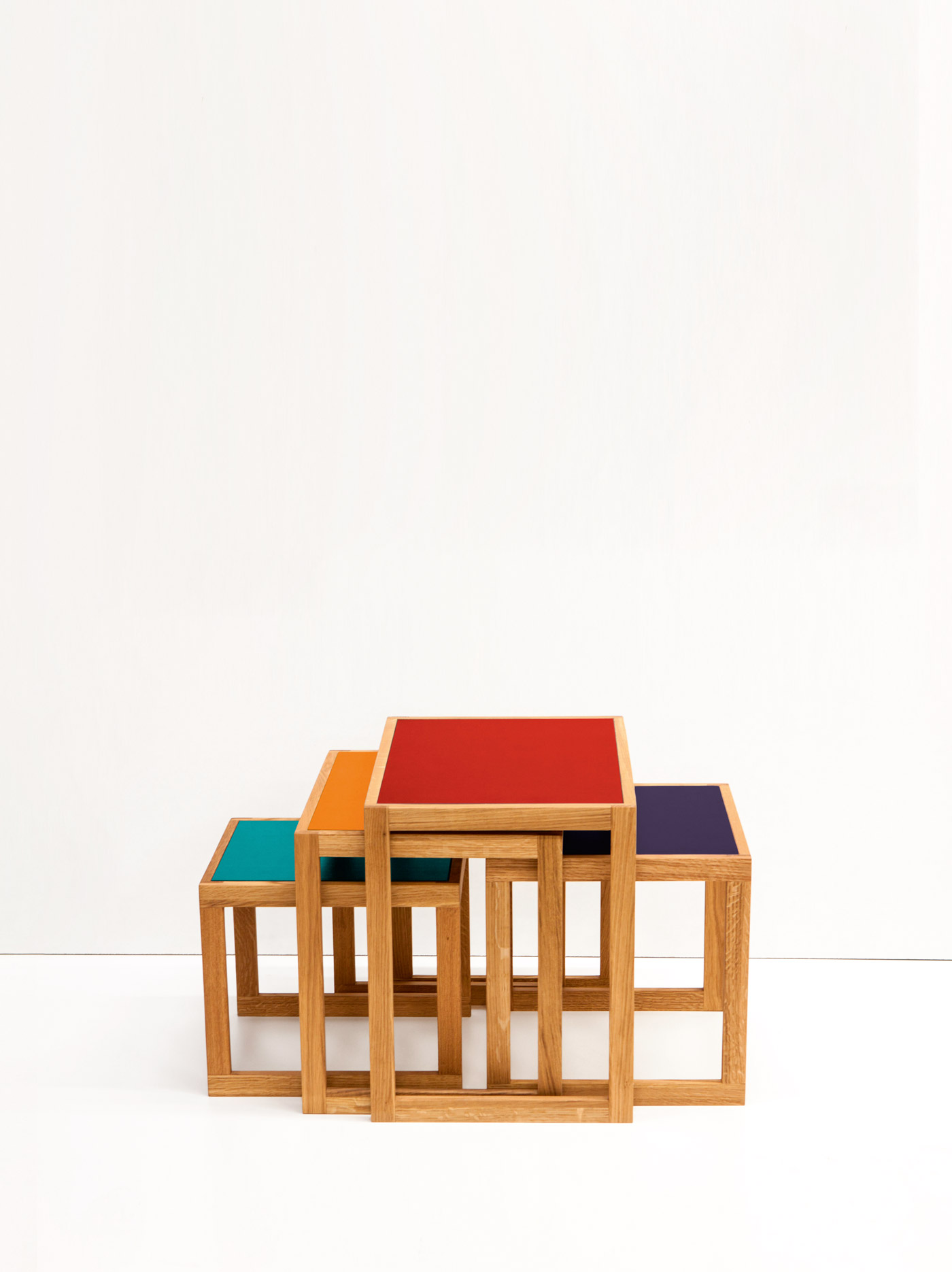 Vier Satztische mit farbigen Tischplatten in Rot, Lila, Orange und Türkis.